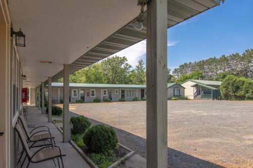 a porch of a building with chairs and a parking lot at Lumber Jill Lodge 17 King Bed Retreat in Balsam Lake