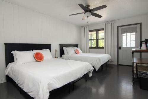 two beds in a white room with a ceiling fan at Lumberjill Lodge 13 Double Queen Room in Balsam Lake