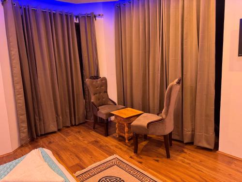 two chairs and a table in a room with curtains at Adu's Eternal Comfort in Leh