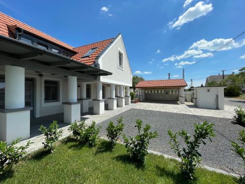 a white house with red roofs and a driveway at Papoula Vendégház - Köveskál in Köveskál