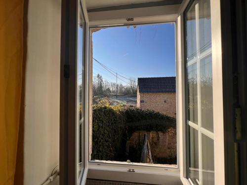 an open window with a view of a yard at La Petite Ecluse, maison d'artistes in Tanlay