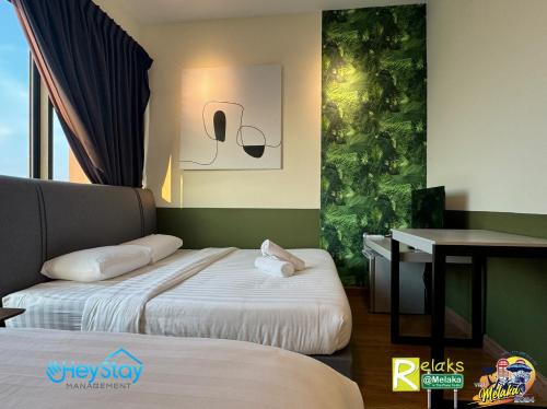a hotel room with two beds and a desk at The Apple Residence By Heystay Management in Melaka