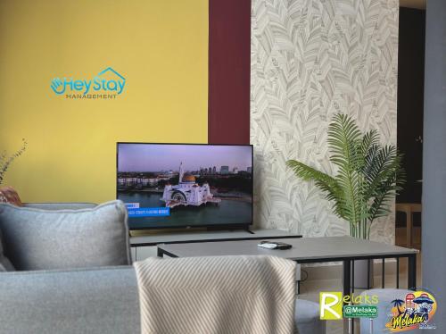 a living room with a tv and a table at The Apple Residence By Heystay Management in Melaka
