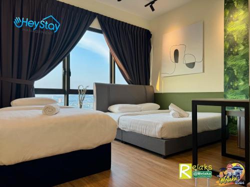 two beds in a room with a window at The Apple Residence By Heystay Management in Melaka