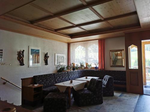 a living room with a couch and a table and chairs at Hotel Sonnblick in Kartitsch