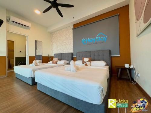 two beds in a room with a sign on the wall at The Apple Residence By Heystay Management in Melaka