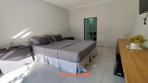 a bedroom with a bed and a desk in a room at Suíte em Delfinópolis a 700m da Represa in Delfinópolis