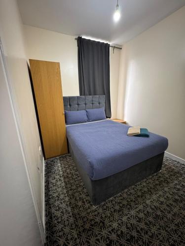 a small bedroom with a bed with blue sheets at Whitefield Guesthouse in Glasgow