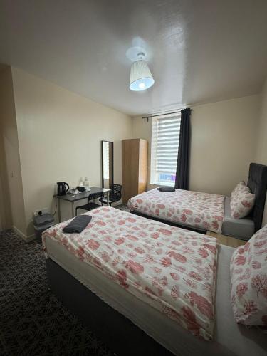 a hotel room with two beds and a desk at Whitefield Guesthouse in Glasgow