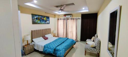 a bedroom with a bed with a blue blanket and a chair at 1 BHK Paradise in Rawalpindi