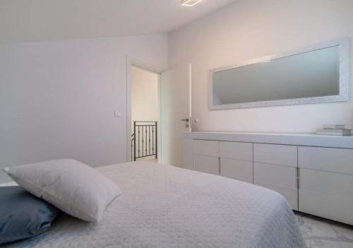 a white bedroom with a large bed and a tv at Luxury Apartment Queens on two floors with a panoramic sea view in Dramalj