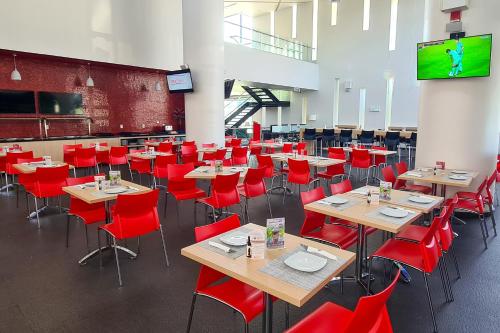 a dining hall with tables and red chairs at Ramada Encore by Wyndham Queretaro in Querétaro