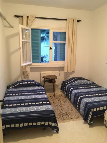 two beds in a room with a window at Appartement 3 chambres bords de mer Hammamet in Nabeul