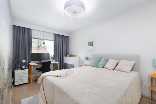 a bedroom with a bed and a desk and a television at Downtown Oulu 2BR, Sauna & Sea View Balcony in Oulu