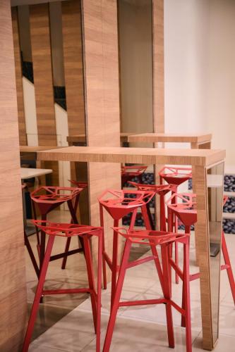 a bar with red stools around a wooden table at KIWI-Taichung Station Branch 1 in Taichung