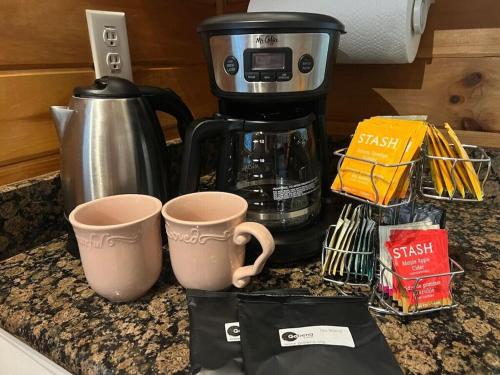 two coffee cups sitting on a counter with a coffee maker at Peaceful Hideaway Treehouse near Little River Canyon in Fort Payne