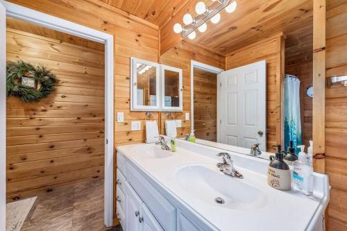 a bathroom with a white sink and a mirror at Peaceful Hideaway Treehouse near Little River Canyon in Fort Payne