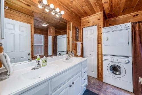 a bathroom with a sink and a washer and dryer at Peaceful Hideaway Treehouse near Little River Canyon in Fort Payne