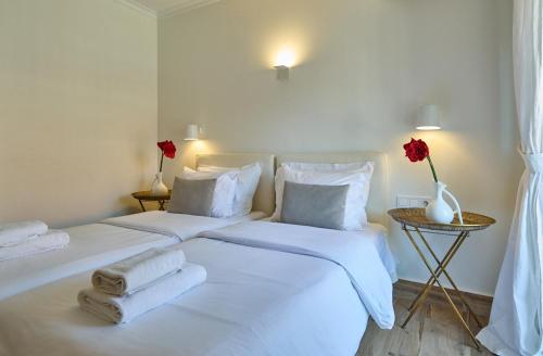 a white bedroom with two beds with towels on them at Afroditi Arhontiko in Litochoro