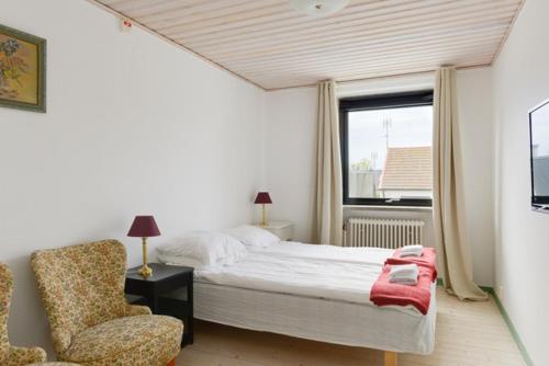 a bedroom with a bed and a chair and a window at Branteviks Bed o Breakfast in Brantevik