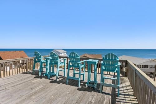 eine Reihe von Stühlen auf einer Promenade neben dem Strand in der Unterkunft Amazing View in Nags Head