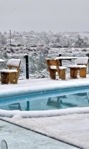 a swimming pool covered in snow with two benches at Complejo Apus in La Cumbrecita