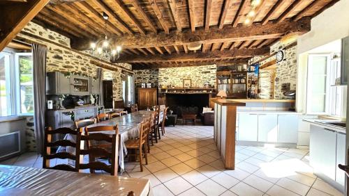 a dining room with a long table and a kitchen at Gîte de France "les volets bleus" 3 épis - Gîte de France 12 personnes MAE-9484 in Espartignac