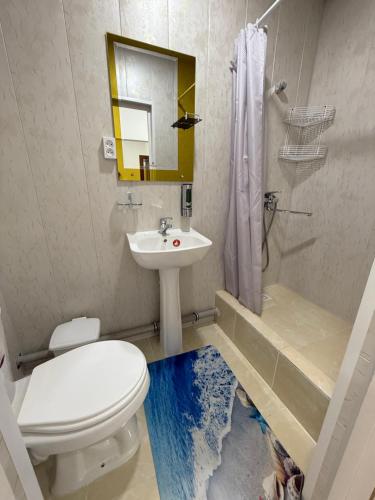 Un baño con inodoro, lavabo y espejo. en KAMIR Guest House, en Bukhara