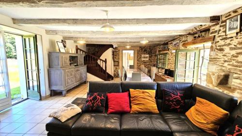a leather couch in a living room with a stone wall at Gîte de France Le rouzeyrol 3 épis - Gîte de France 12 personnes MAE-9674 in Charbonniers