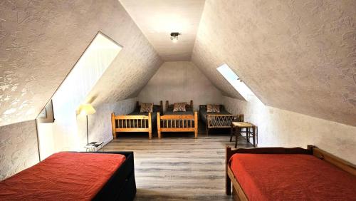 a attic room with two beds and two chairs at Gîte de France Le rouzeyrol 3 épis - Gîte de France 12 personnes MAE-9674 in Charbonniers