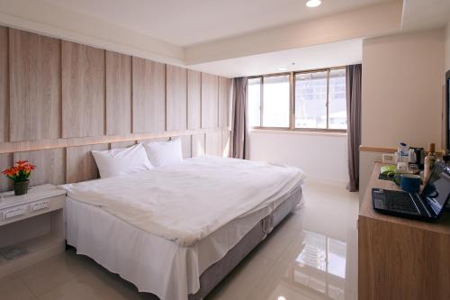 a bedroom with a bed and a desk with a laptop at KIWI-Taichung Station Branch 1 in Taichung