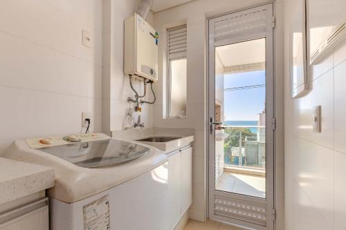a white bathroom with a sink and a window at Boulevard: Apto Exclusivo a Passos do Mar in Bombinhas