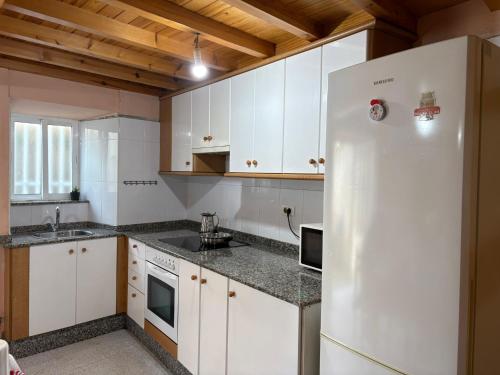 a kitchen with white cabinets and a white refrigerator at casa en Cedeira in Cedeira
