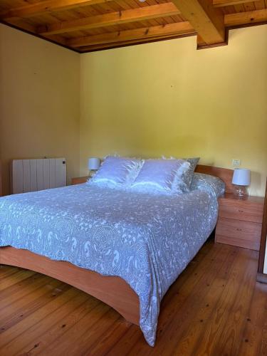 a bedroom with a bed with blue sheets and wooden floors at casa en Cedeira in Cedeira