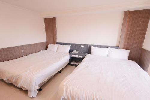 two beds in a room with white sheets at KIWI-Taichung Station Branch 1 in Taichung