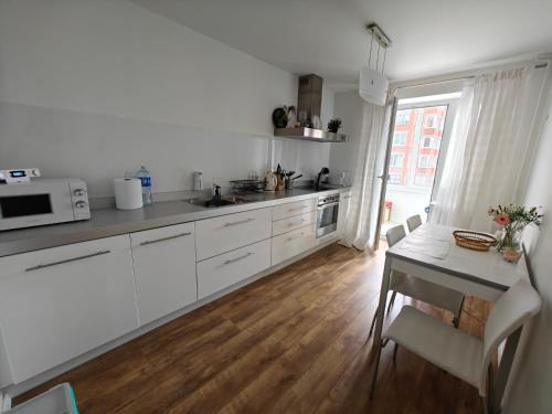 a kitchen with white cabinets and a table with a microwave at Holiday Ap in Visaginas