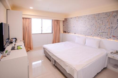 a bedroom with a large white bed and a tv at KIWI-Taichung Station Branch 1 in Taichung