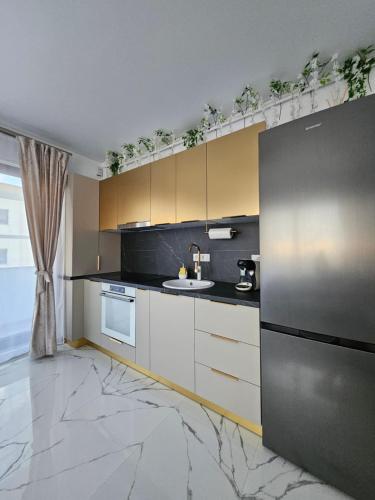 a kitchen with white cabinets and a black refrigerator at EverGreen Apartment4 in Năvodari