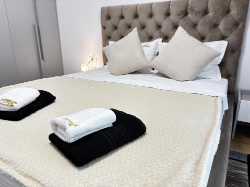 a bed with two pillows and towels on it at Monarch Luxury Apartment in Timişoara