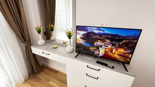 a flat screen tv sitting on a white dresser at Monarch Luxury Apartment in Timişoara