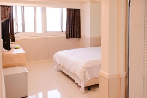 a bedroom with a bed and a desk and a television at KIWI-Taichung Station Branch 1 in Taichung