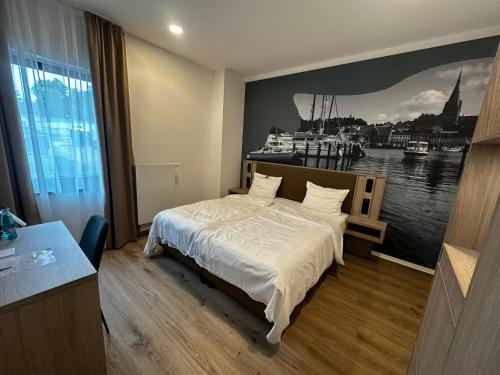a bedroom with a bed and a painting of a harbor at Central Hotel in Flensburg