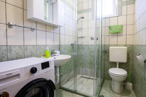 a bathroom with a toilet and a sink and a washing machine at Apartment with Pool "Sunset Cove" in Neum