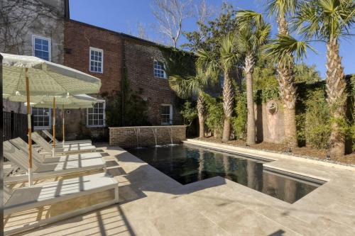 een zwembad met ligstoelen en een gebouw met palmbomen bij The Nicholas Veranda King Suite - Walk to King in Charleston