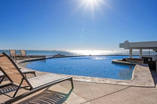 a pool with chairs and the ocean in the background at Las Palmas 4BR 4BA Penthouse OV 701 in Campo del Medio
