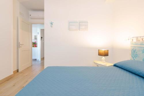 a bedroom with a blue bed and a lamp on a table at Domo Green House in Villasimius