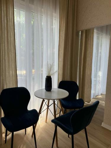a table with three chairs and a table with a vase on it at Leśna Przystań in Pojezierze