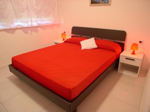 um quarto com uma cama vermelha com duas mesas de cabeceira em Appartamento Costa Azzurra em Grado