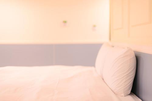 a bedroom with a white bed and a white door at KIWI-Taichung Station Branch 1 in Taichung