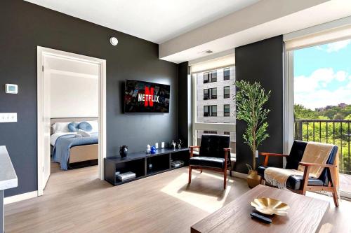 a living room with a bed and a television on a wall at E501 Spacious & Stylish 2bedroom Condo In Downtown Minneapolis, Minutes From Minneapolis Convention Center & US Bank Arena in Minneapolis